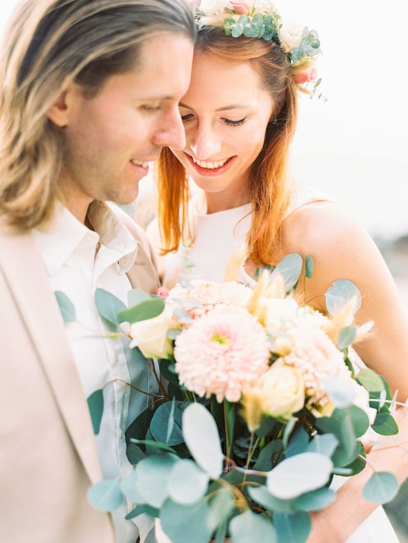 Novia y novio mirando un ramo de flores